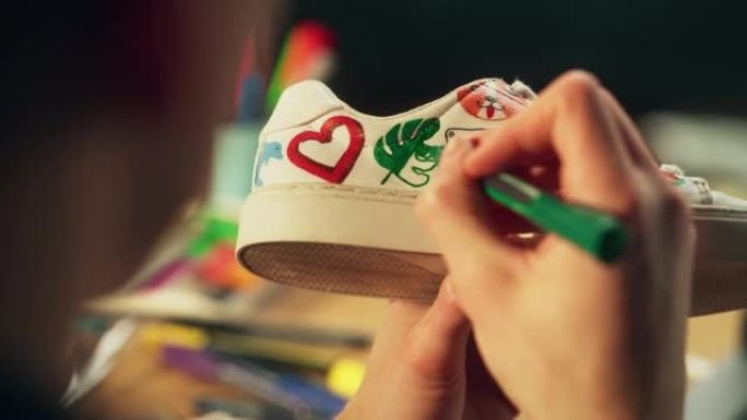 艺术家手的镜头，在鞋子上拿着记号笔和绘图设计。Painter创建定制的运动鞋并制作自己的作品。千禧一