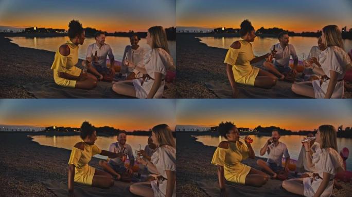 SLO MO年轻的朋友在黄昏时在海滩上用冷饮敬酒