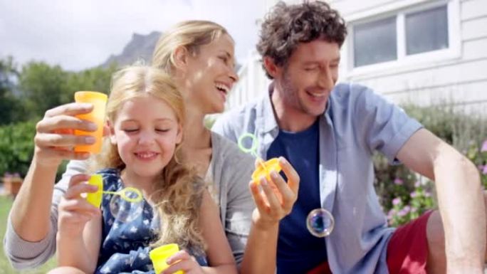 一个小女孩和她的父母一起在户外吹泡泡的4k视频片段