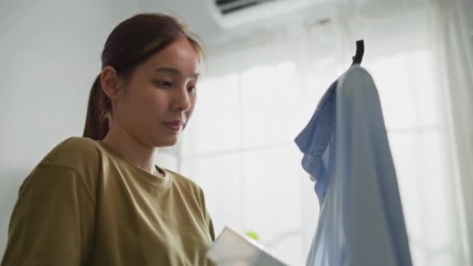 女人站在客厅里熨衣服