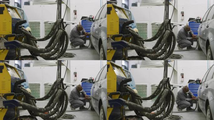 非裔美国男汽车修理工戴口罩用研磨机打磨汽车侧面