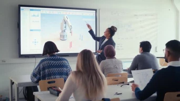 黑人老师向学生解释工程学，并指向带有机械臂工作程序的投影屏幕。聪明的未来开发者认真倾听。计算机科学教