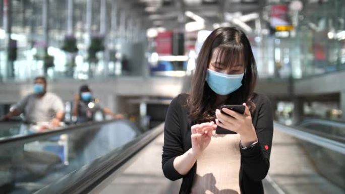 在机场使用智能手机戴口罩的女人
