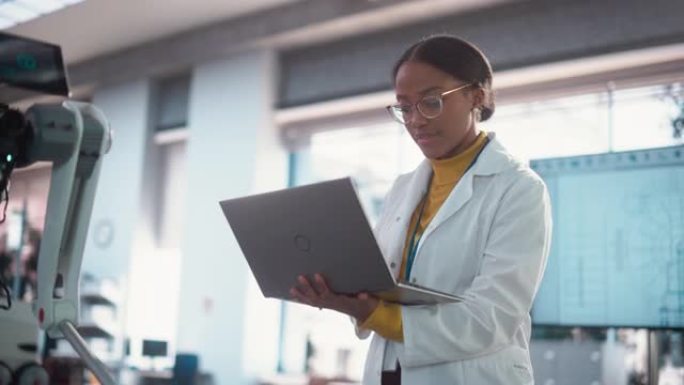 穿着实验室外套的年轻黑人女性专家的肖像微笑着使用笔记本电脑。专业而成功的女性担任工程师，开发高科技项