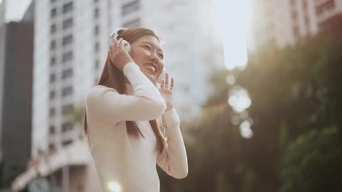 女人在城市放耳机和享受音乐