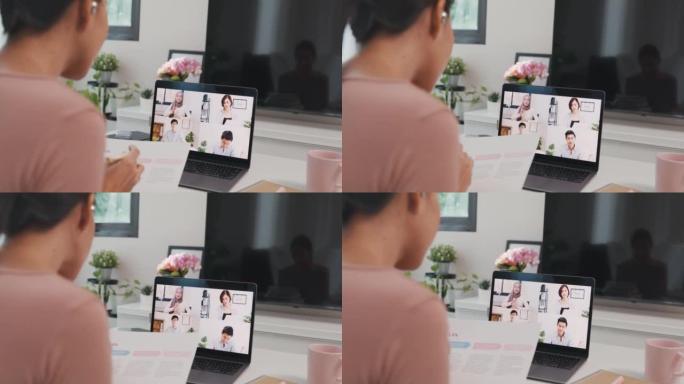 年轻的亚洲女商人在客厅在家工作时，使用笔记本电脑与同事讨论视频通话会议的计划。