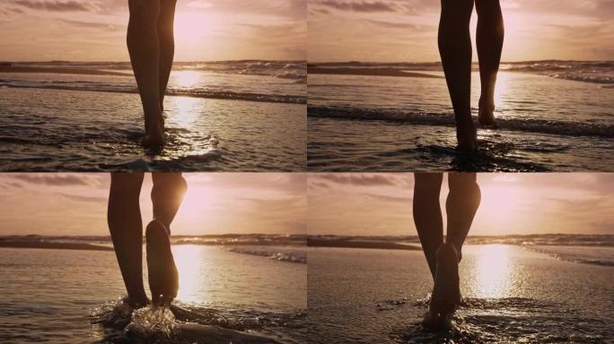 美丽的女人光着脚走在夏天的海滩特写。孤独快乐的女孩在海水中游泳休息的浪漫概念。在自然光线下的沙滩海景