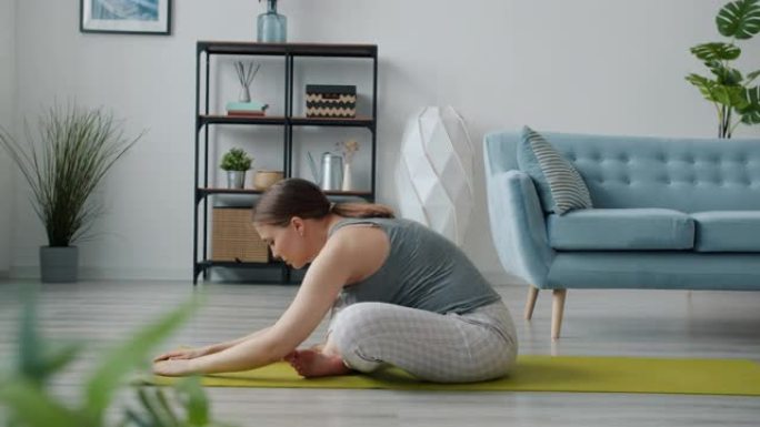 活跃的未来母亲享受瑜伽在垫子上伸展身体，然后放松触摸腹部