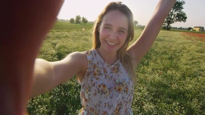 一个年轻的金发幸福的女人的真实镜头正在田野里打视频电话。