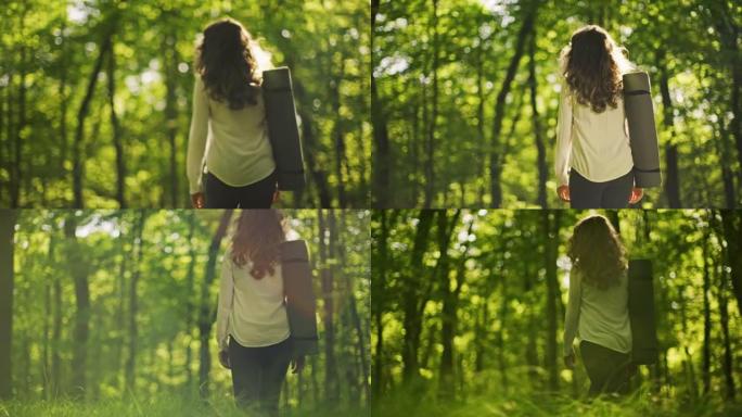 SLO MO无法识别的年轻女子在阳光明媚的绿色森林中行走