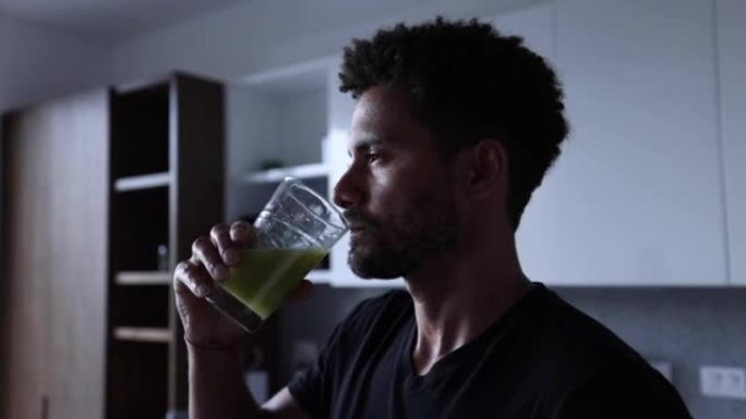 英俊的黑人男子享受绿色果汁的侧写视图