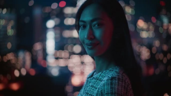 美丽的亚洲女性肖像深夜站在霓虹灯下的城市街道上。地道的成年自信女人在镜头前摆姿势，在市中心商业街的夜
