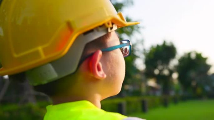 这位男孩戴着安全硬度和工作头盔的肖像，作为一名工程师站在父母面前玩耍。