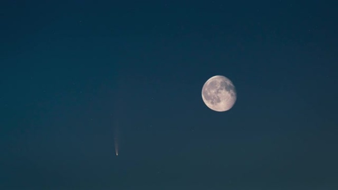 傍晚星空背景上的月亮和飞行彗星