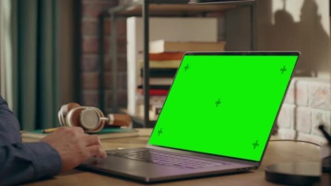 在带有绿屏显示的笔记本电脑上，使用触控板的人在家中工作的男性双手。学生做作业，为学校考试而学习。检查