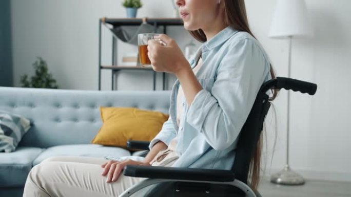 年轻的残疾女士独自坐在轮椅上喝茶的肖像