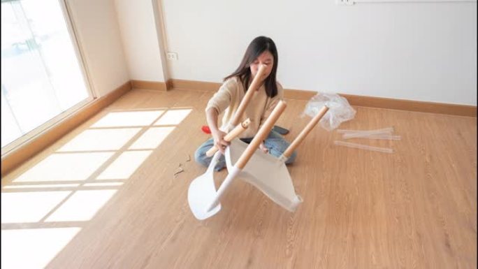 在空荡荡的新房间里组装DIY椅子的亚洲女性