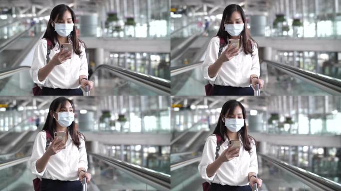 带口罩的亚洲女性使用手机在机场旅行，带口罩的新常态旅行