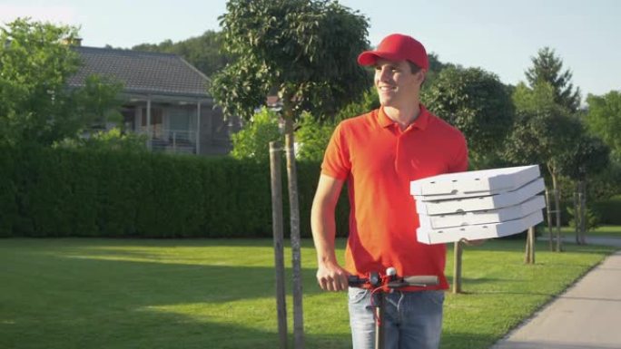 穿着红色衬衫的快递员在电动踏板车上运送比萨饼时微笑