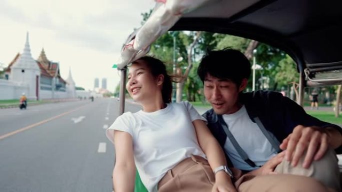 年轻夫妇乘坐Tuk Tuk旅行时欣赏城市景观。