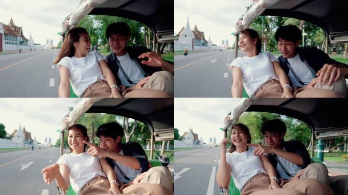 年轻夫妇乘坐Tuk Tuk旅行时欣赏城市景观。