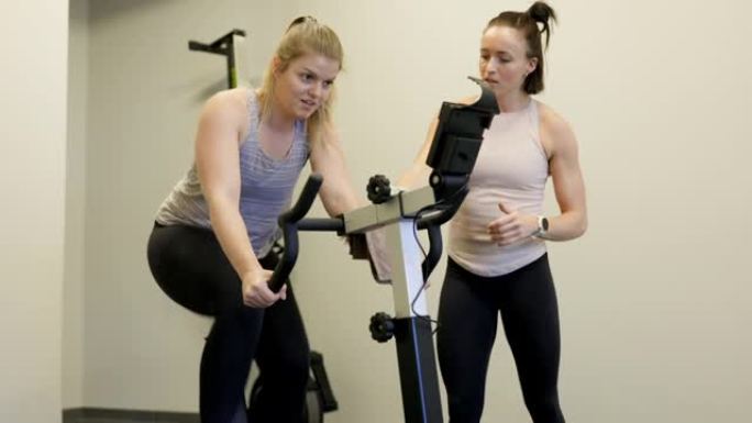女教练激励女性在固定自行车上锻炼