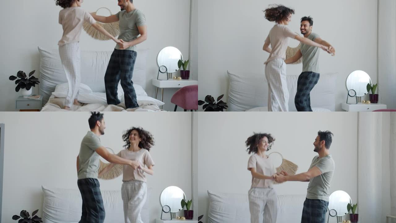 穿着睡衣的阿拉伯男人和高加索女人的慢动作在家里的床上跳舞和大笑