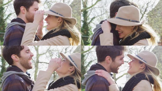 当男人碰上女人的帽子时，夫妻俩一起笑着一起走过秋天的公园