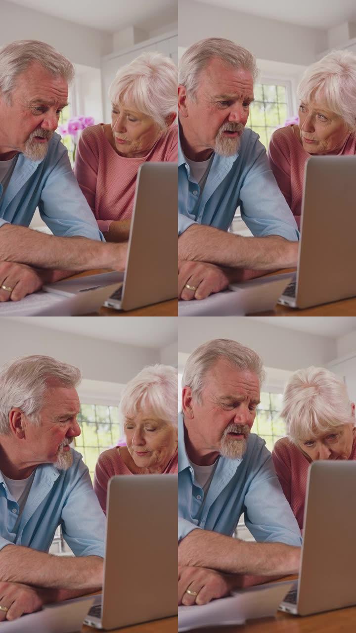 生活成本危机期间，退休老年夫妇在家厨房里担心的垂直视频，账单和笔记本电脑看起来很焦虑-慢动作拍摄