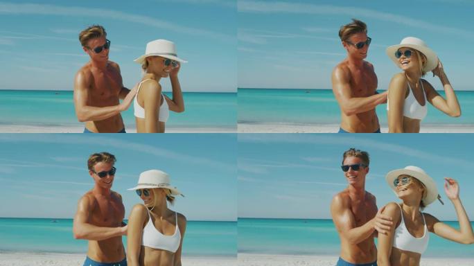 幸福的年轻夫妇的慢动作很有趣，可以在海滩度假期间涂上防晒霜或晒黑乳液来照顾他们的皮肤。