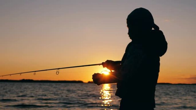 一个男孩正在日落湖附近处理钓鱼竿