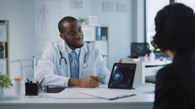 非裔美国医生在健康诊所的平板电脑上向患者展示乳房x光检查结果。友好的助手解释了乳腺癌预防筛查的重要性