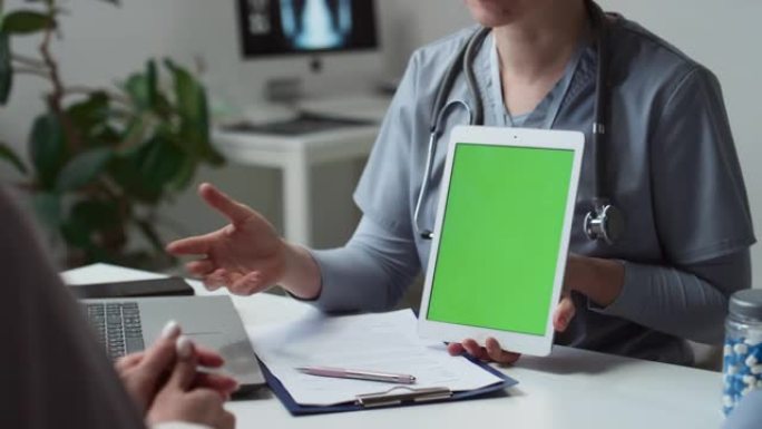 临床医生在演示时拿着空白绿屏的平板电脑