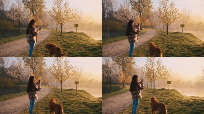 年轻女子与狗站在一起时在雾湖拍照