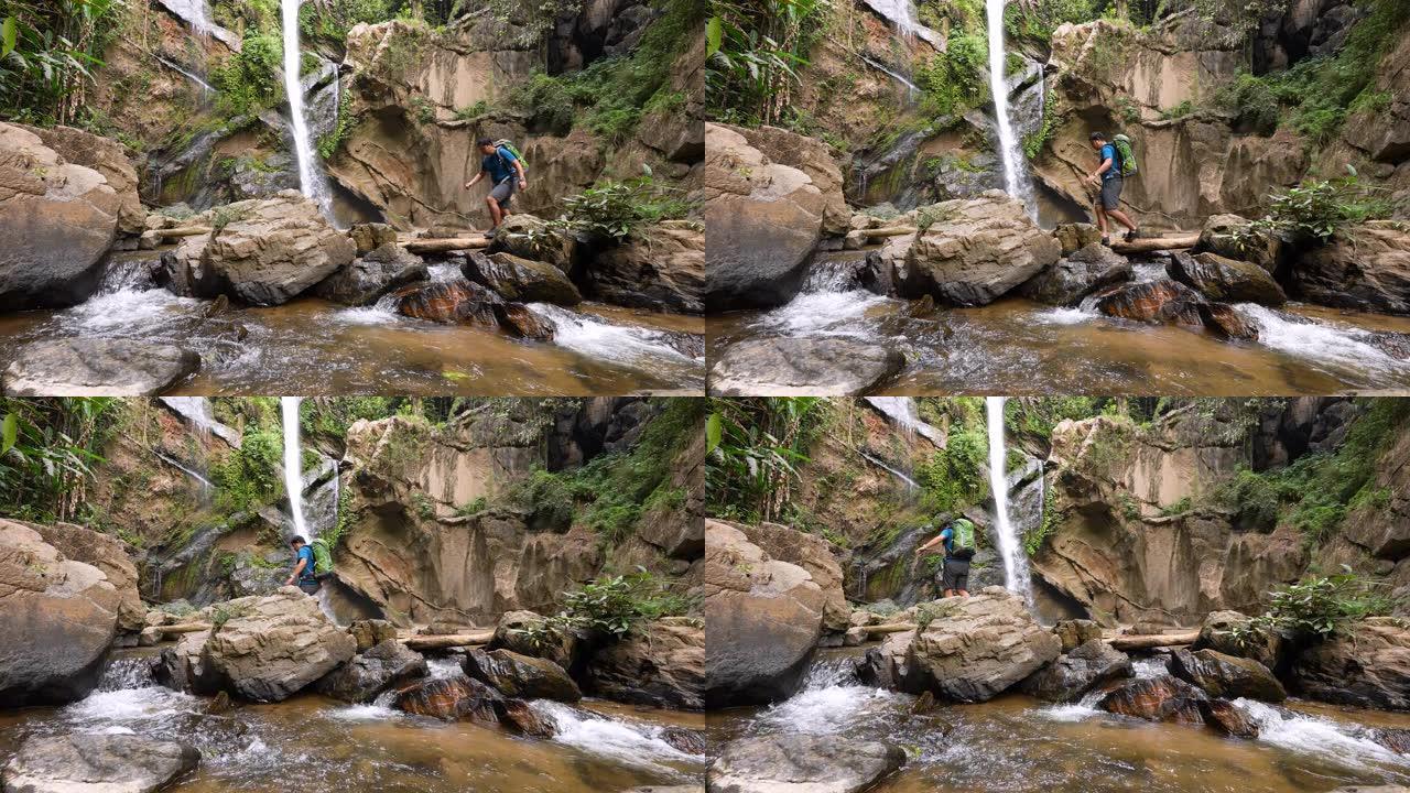 雄性徒步旅行者在雨林中徒步旅行在绿色森林中的小溪瀑布探险