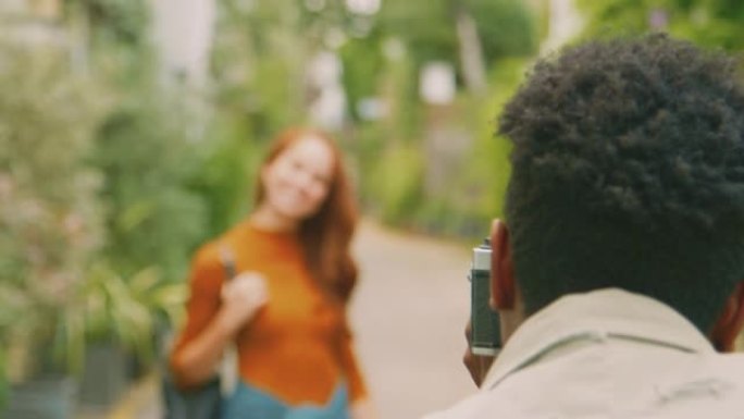 年轻夫妇一起穿越城市时，女人摆姿势，男人在相机上拍照