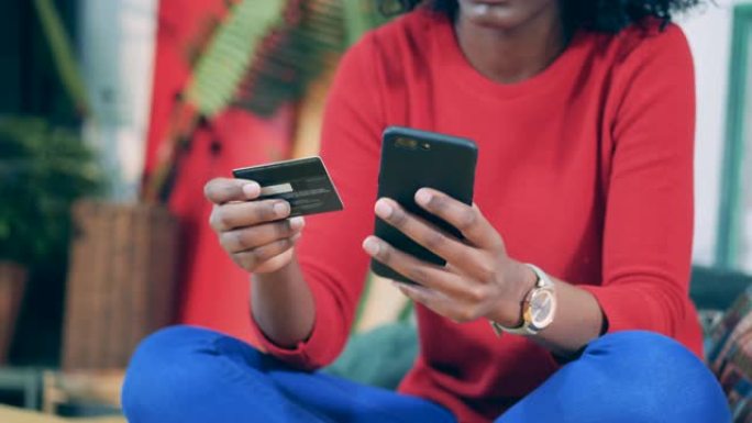 非洲妇女在网上购物时拿着电话和卡