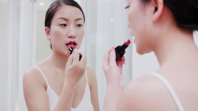 漂亮年轻的亚洲女人在镜子前化妆