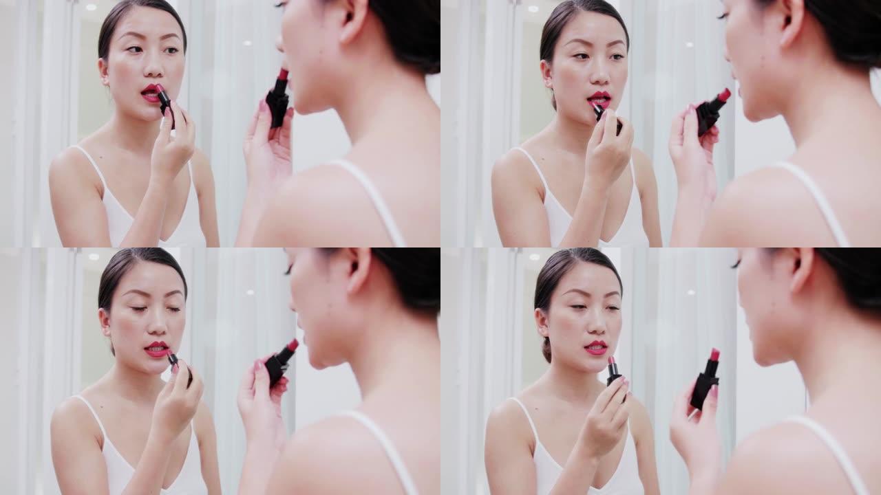 漂亮年轻的亚洲女人在镜子前化妆