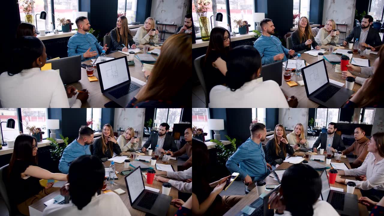 团队合作理念。快乐的男经理在商业团队办公室会议慢动作中与多民族团队分享想法。