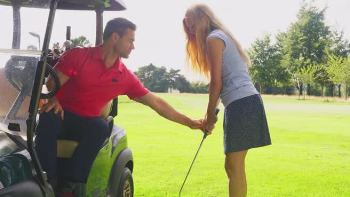 高尔夫球车中的男人在与高尔夫俱乐部练习时向女人提供建议
