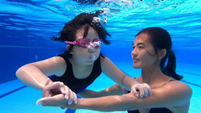 亚裔华裔少女与教练在水中练习呼吸练习