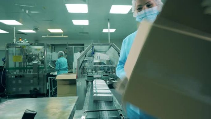 女药理学工作者正在使用胶带包装盒子