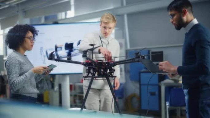 年轻的工程师在现代科学实验室为无人机创建创新计划。航空专家团队在新的无人机上工作，进行讨论，使用笔记