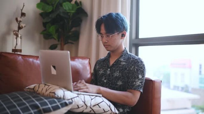 亚洲中国十几岁的男孩在周末使用笔记本电脑坐在客厅的沙发上