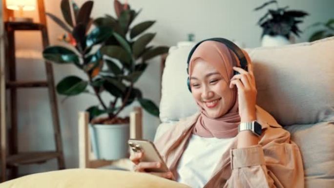 亚洲穆斯林女孩喜欢并喜欢在手机上听音乐和观看在线媒体。