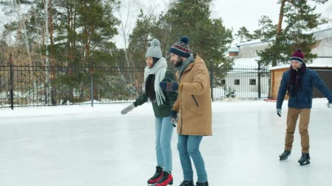 快乐的情侣在公园滑冰，手拉着手一起玩乐