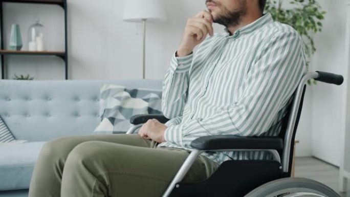 孤独的残疾人的肖像坐在轮椅上，悲伤的脸在家里思考