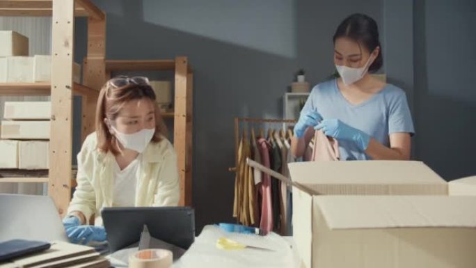 专业两位亚洲女士休闲服防护手套外科口罩检查库存库存系统准备包装订单衬衫产品发送客户。新型冠状病毒肺炎