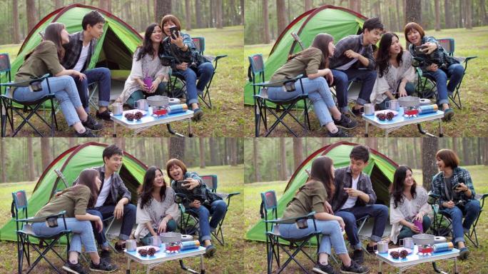 一群朋友在露营地放松和露营，用智能手机自拍有趣